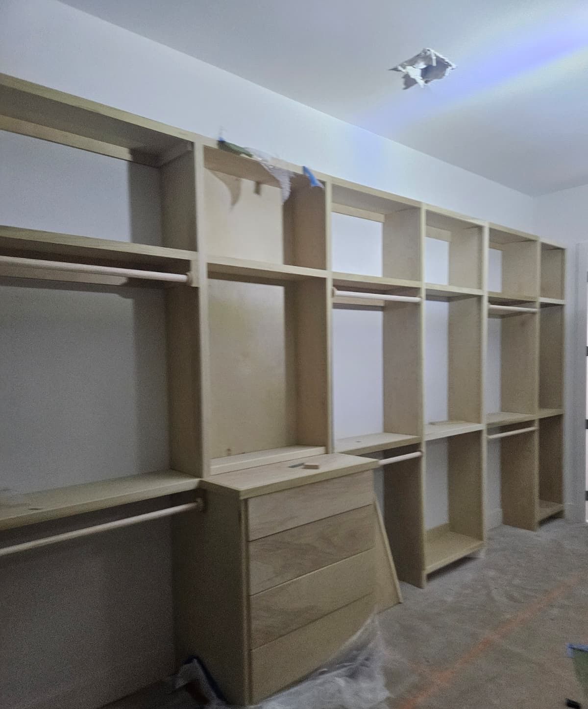 Full closet wall of built-in shelving sections and hanging rods