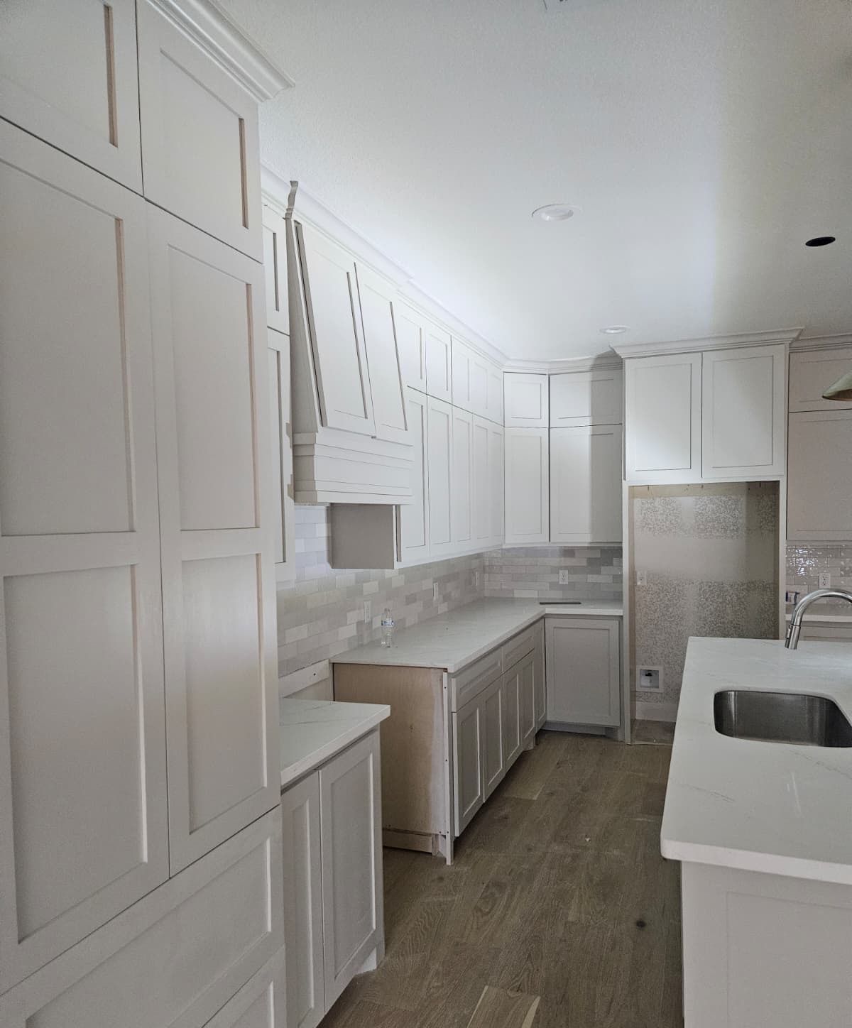 Painted kitchen with tall pantry cabinets, wood hood and crown molding to the ceiling