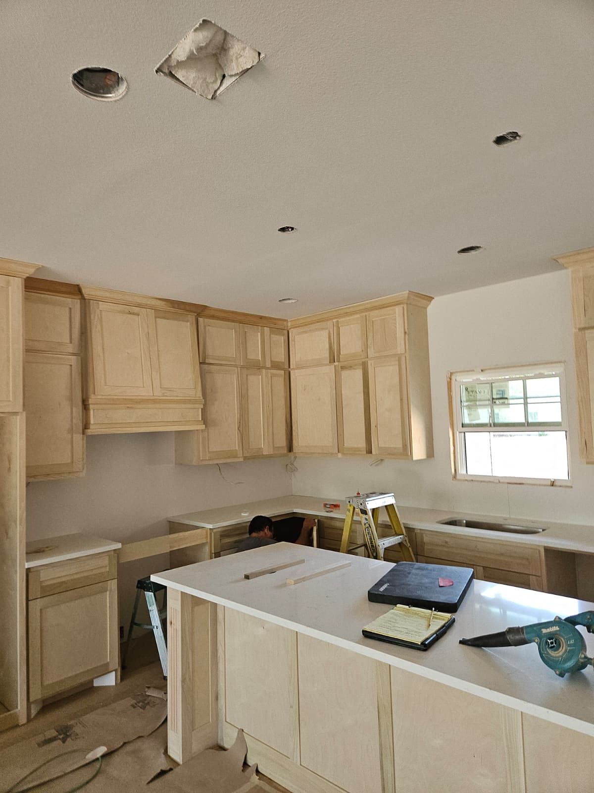 Kitchen mid-install with unpainted cabinets, crown molding and a paneled island