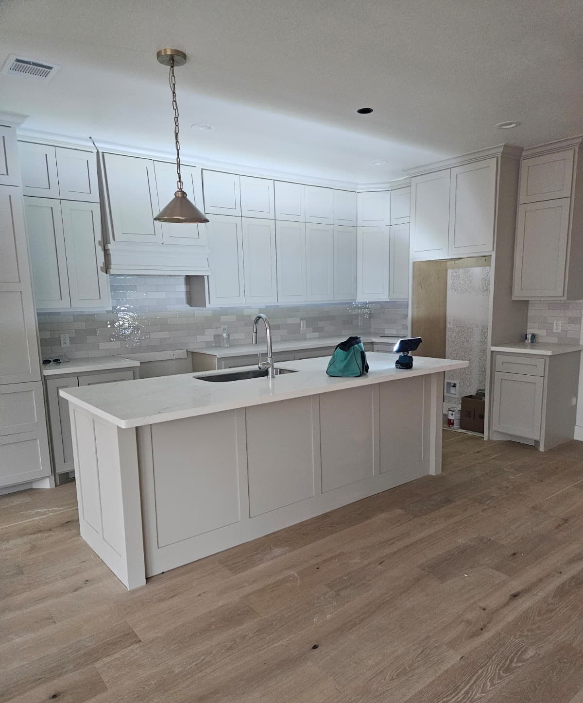 Painted shaker kitchen with stacked upper cabinets, range hood and a paneled island