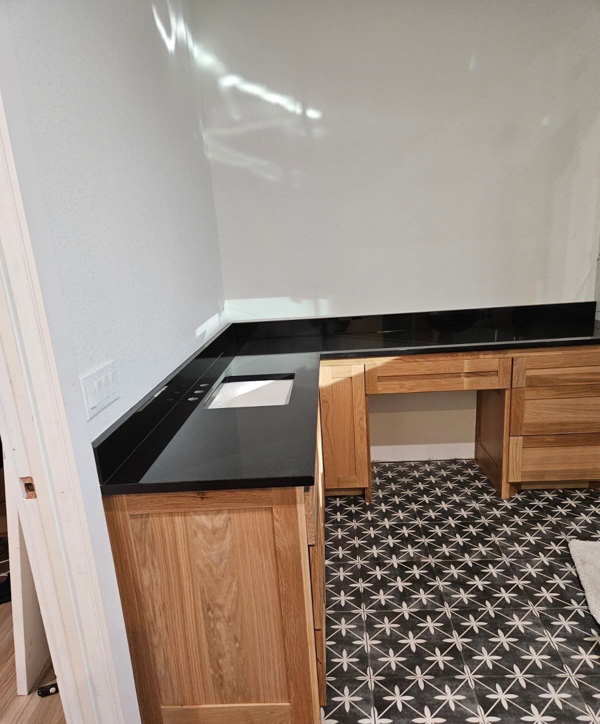 L-shaped run of oak cabinets with a sink base and a built-in desk nook