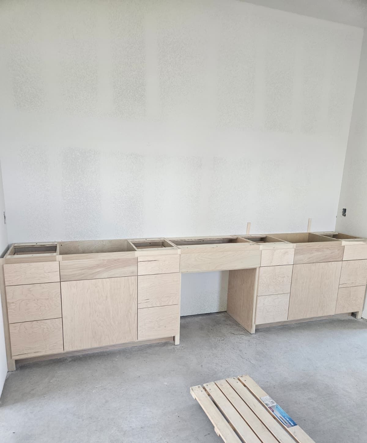 Long cabinet run with drawer banks and a center knee space, before countertops